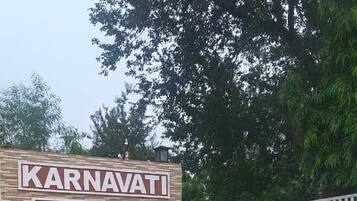 Señal para Karnavati Retreat Resort con entrada vigilada y un coche estacionado.