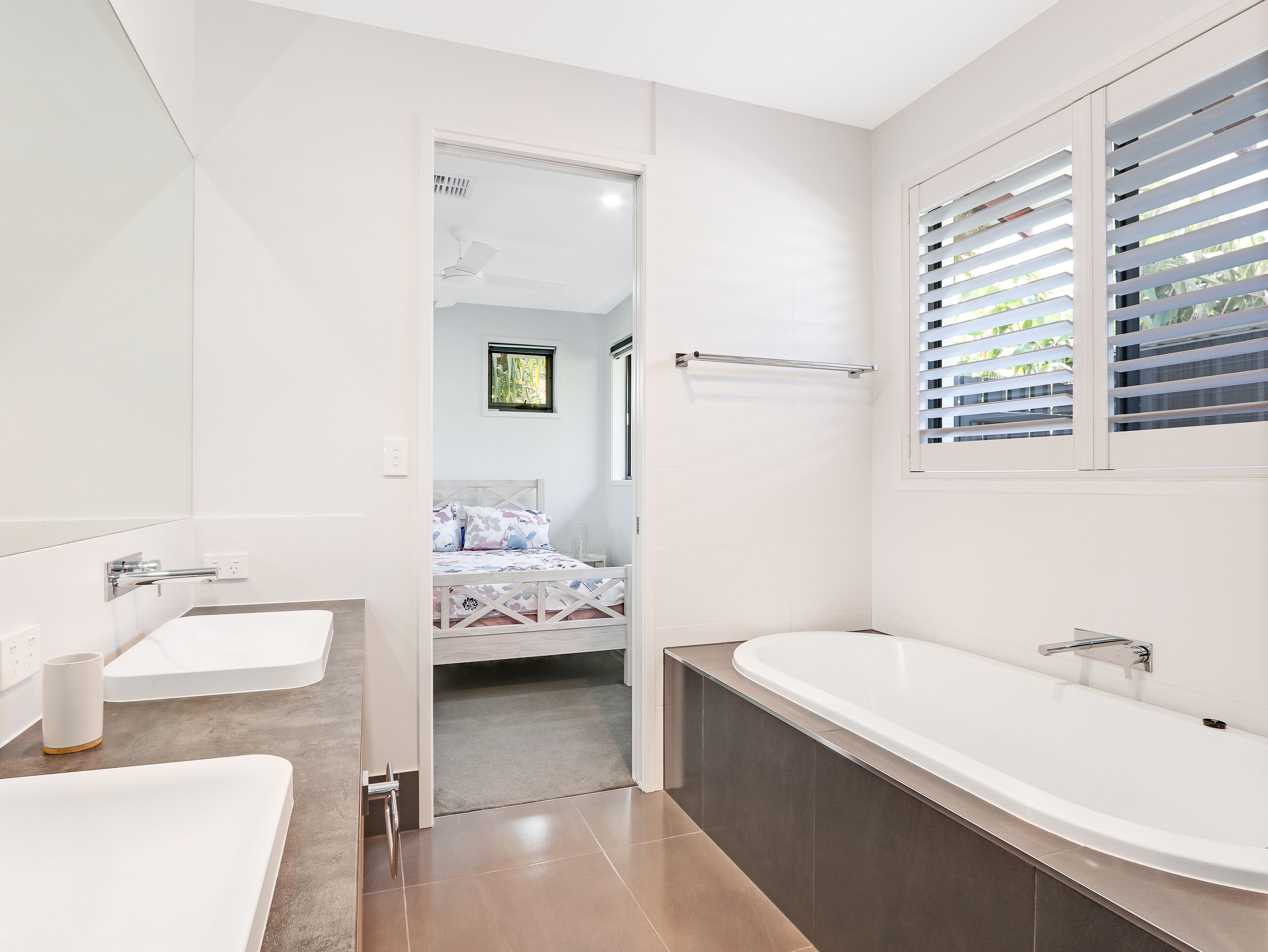 A modern bathroom with a large bathtub, a double sink, and a shower area.