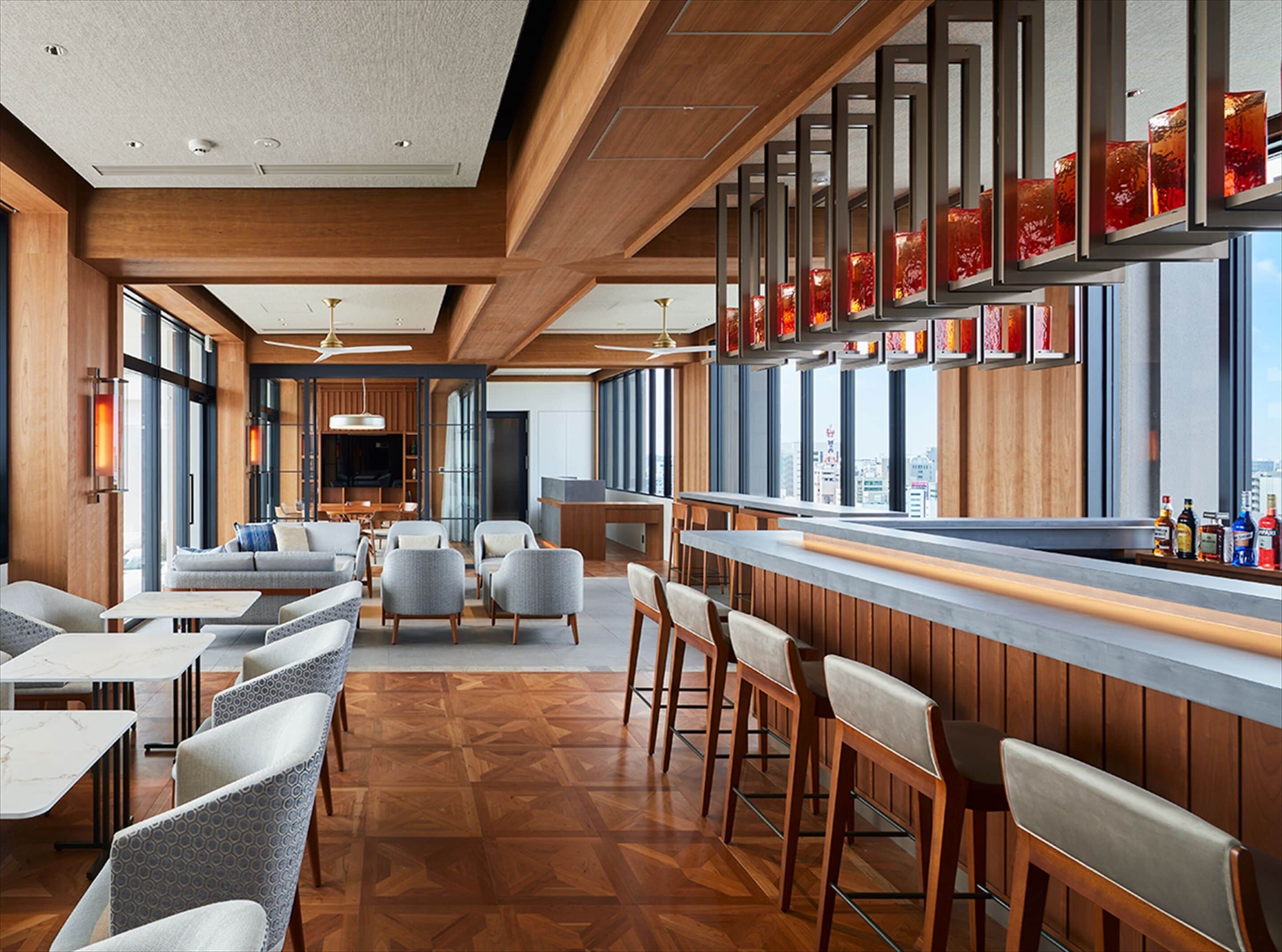 A modern bar area with wooden accents, seating, and a city view.