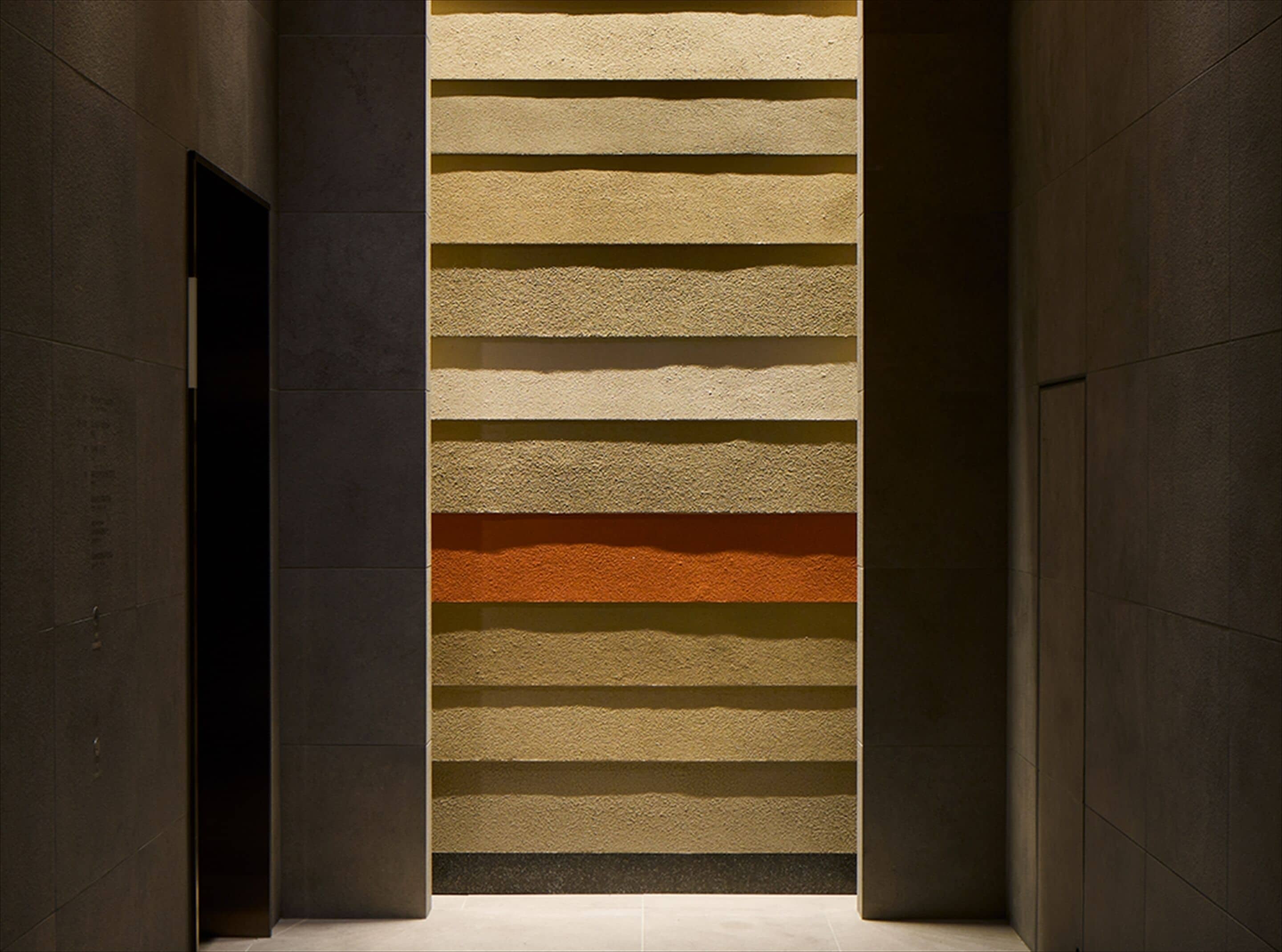 A corridor with a textured wall featuring horizontal stripes in varying shades.