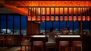 Un bar con vista a la ciudad, taburetes de madera y un techo que se asemeja a lava.