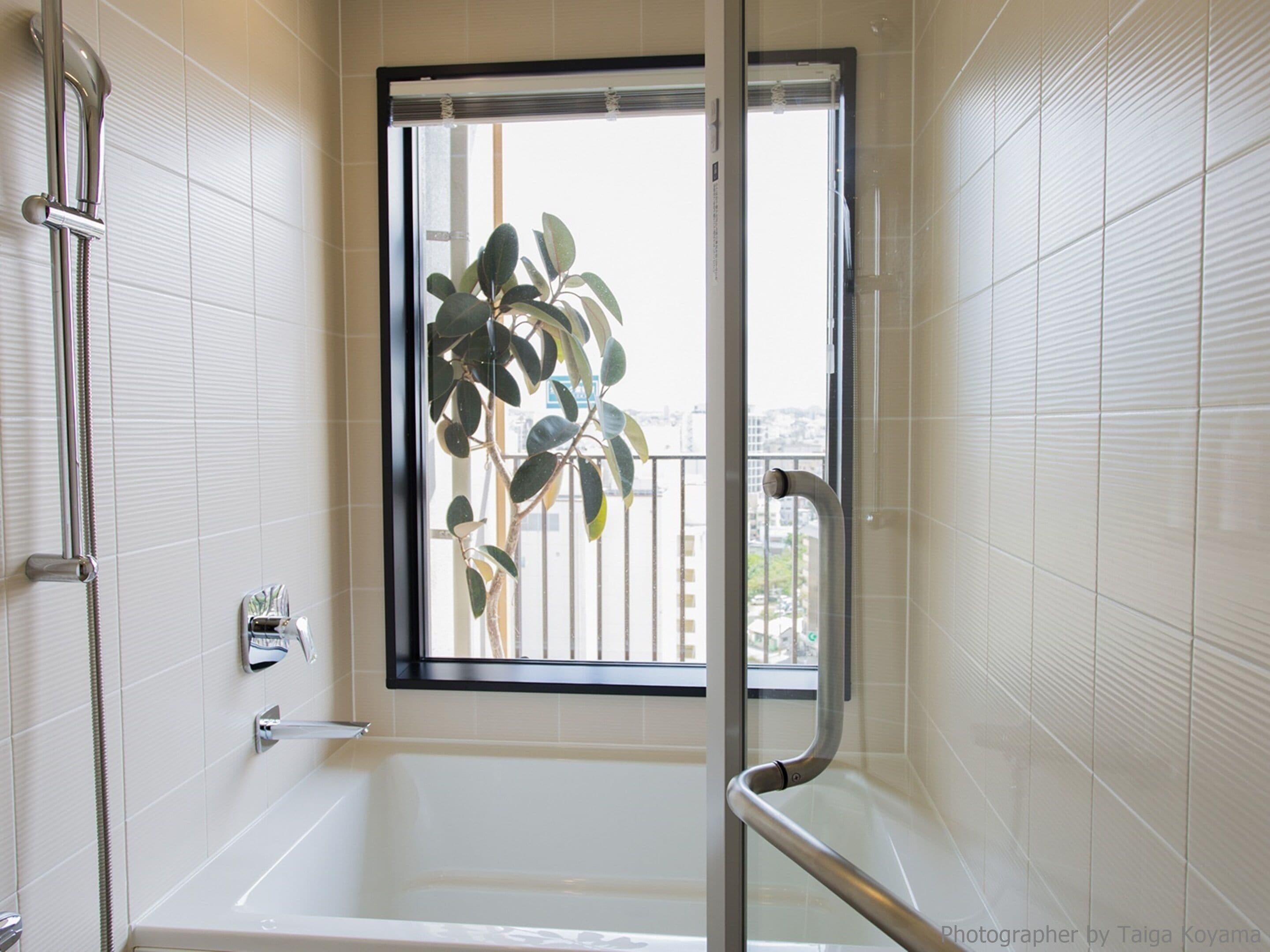 Un baño moderno con bañera, ducha y ventana con vistas a un edificio.