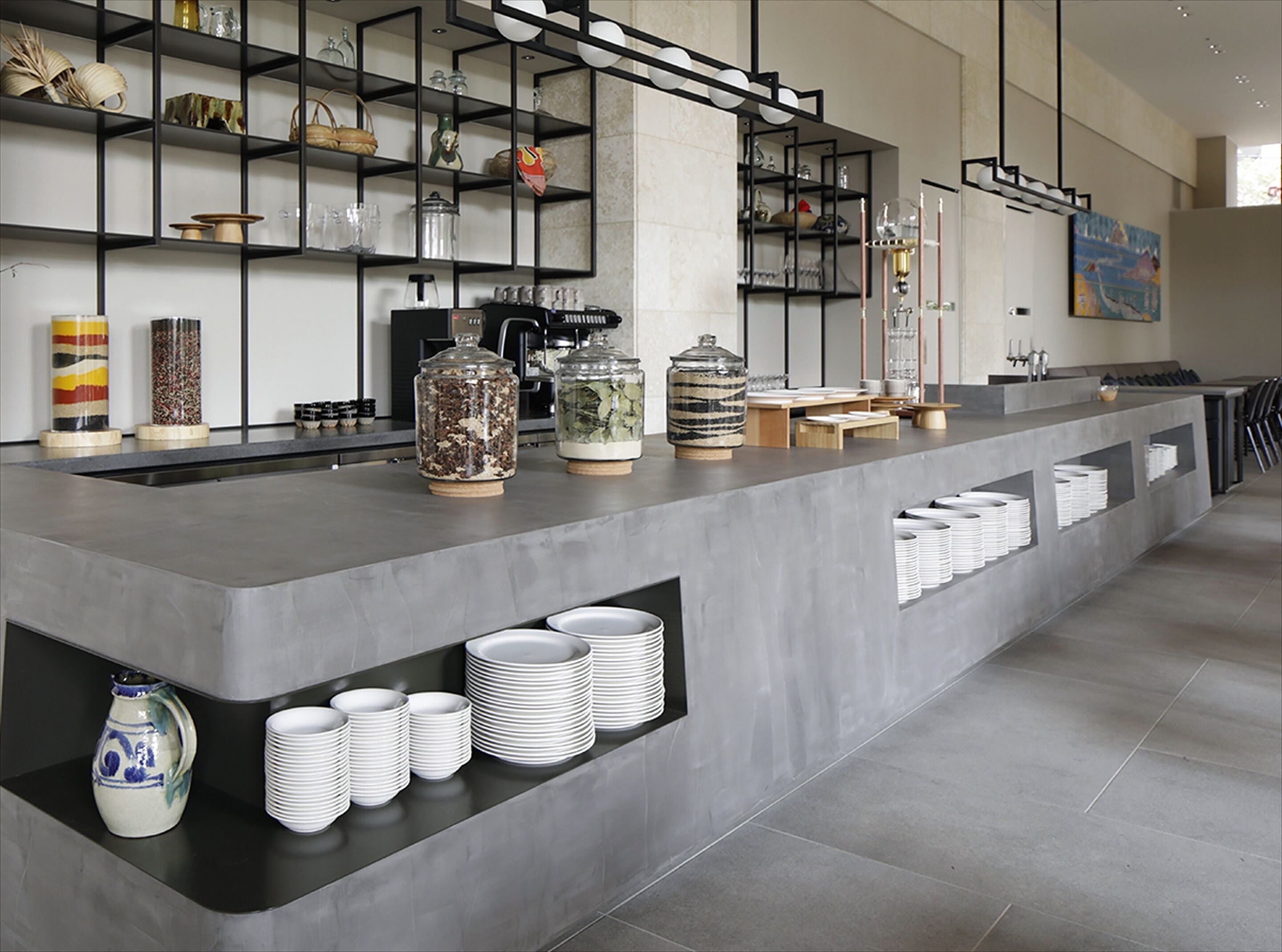 Una cocina moderna con una encimera amplia, estantes con utensilios de cocina y una cafetera.