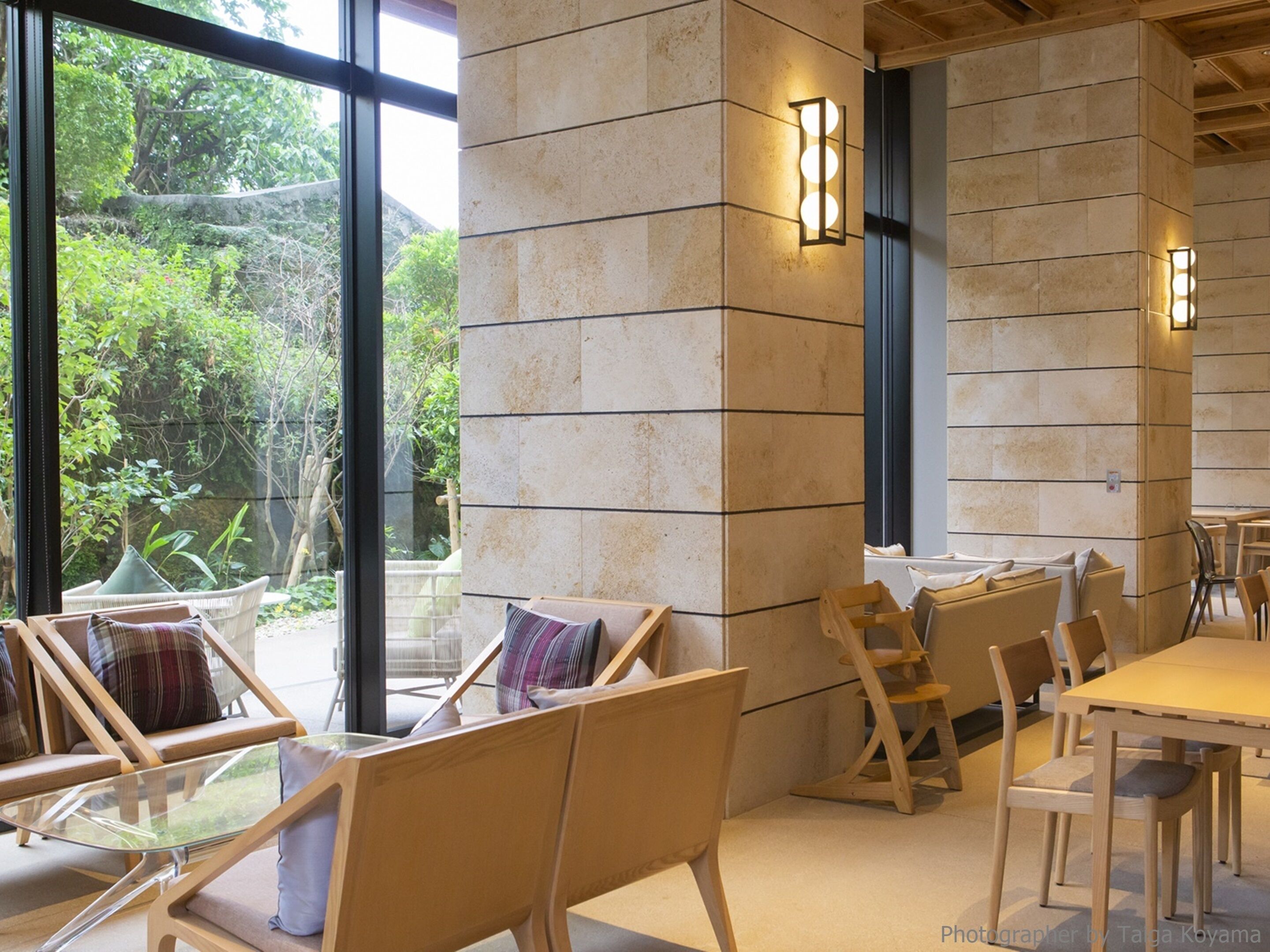 A modern interior with large windows, wooden furniture, and stone walls.