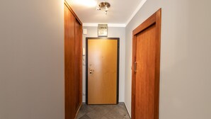 A hallway with wooden doors, a ceiling light fixture, and a framed picture on the wall. - Victus Apartamenty - Avocado (Sopot)
