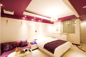 A bedroom with a bed, a nightstand, a dresser, a vanity, and a window with a view. - Coco Hotel Tiara - Adults Only (Shizuoka)