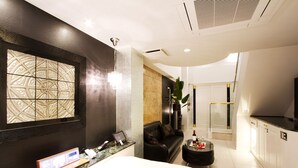 Une chambre d’hôtel moderne dotée d’une grande fenêtre, d’un canapé en cuir noir, d’une table basse en verre et d’un mini-bar.