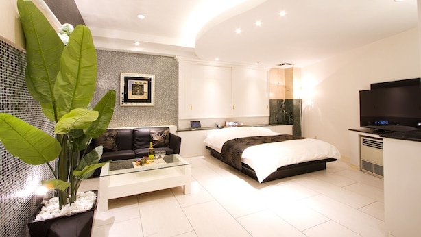 Une chambre d’hôtel moderne avec un grand lit, un canapé, une table basse et un téléviseur.