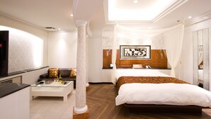 Une chambre d’hôtel moderne équipée d’un lit, d’un canapé, d’une table basse et d’un téléviseur.
