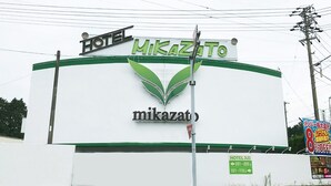 Une enseigne d’hôtel portant le nom « Mikazato » et des flèches indiquant les numéros de chambre 101 à 110 et 201 à 220.