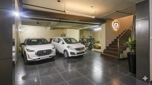 Un parking avec deux voitures blanches garées, un escalier et une plante.