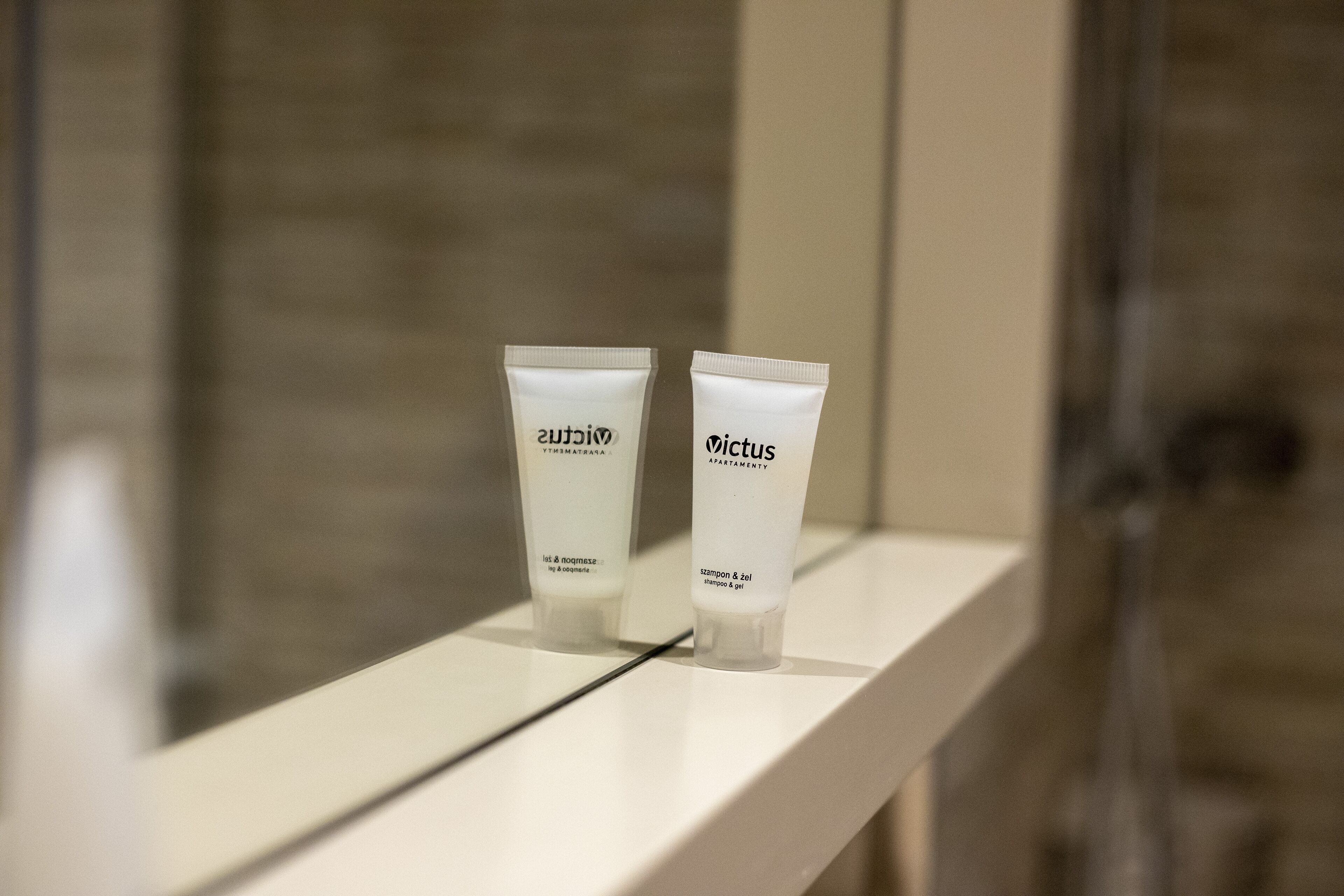 Two tubes of 'Victus' shampoo and conditioner on a white shelf in a bathroom.
