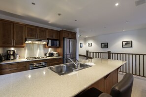 A modern kitchen with wooden cabinets, stainless steel appliances, and a granite countertop. - Ishi Couloir (Kutchan)