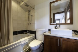 A modern bathroom with a bathtub, toilet, and sink. - Ishi Couloir (Kutchan)