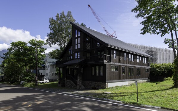A two-story lodge with a steeply pitched roof, large windows, and a stone foundation. - Ishi Couloir (Kutchan)