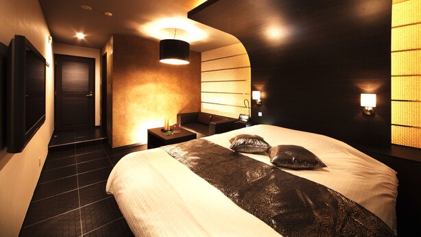 A modern hotel room with a large bed, a bedside table, a nightstand, and a wall-mounted TV. - Hotel Baron -the Sweet Modern - Adults Only (Togo)