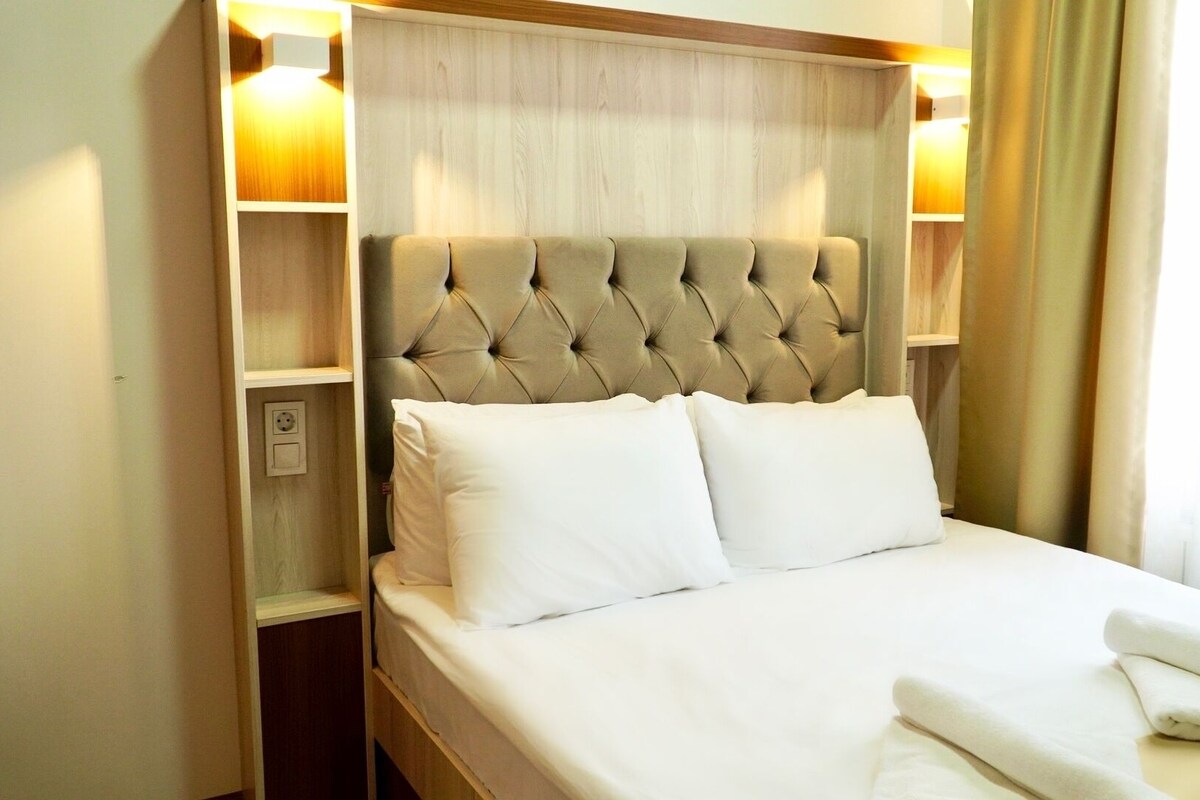 Ein Hotelzimmer mit einer gesteppten Kopfstütze, zwei weißen Kissen und einem ordentlich bezogenen Bett.