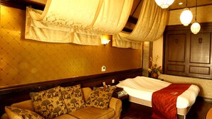 A hotel room with a bed, a sofa, and a nightstand.