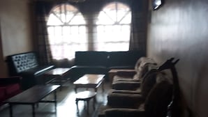 A living room with a sofa set, a coffee table, and a television mounted on the wall.