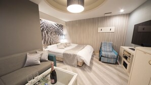 A modern hotel room with a bed, a sofa, a television, and a minibar. - Hotel Dion -dreams IN Resort - Adults Only (Miyoshi)