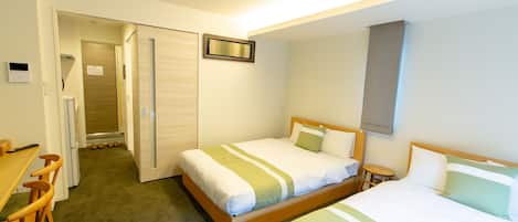 A hotel room with two beds, a desk, and a chair.