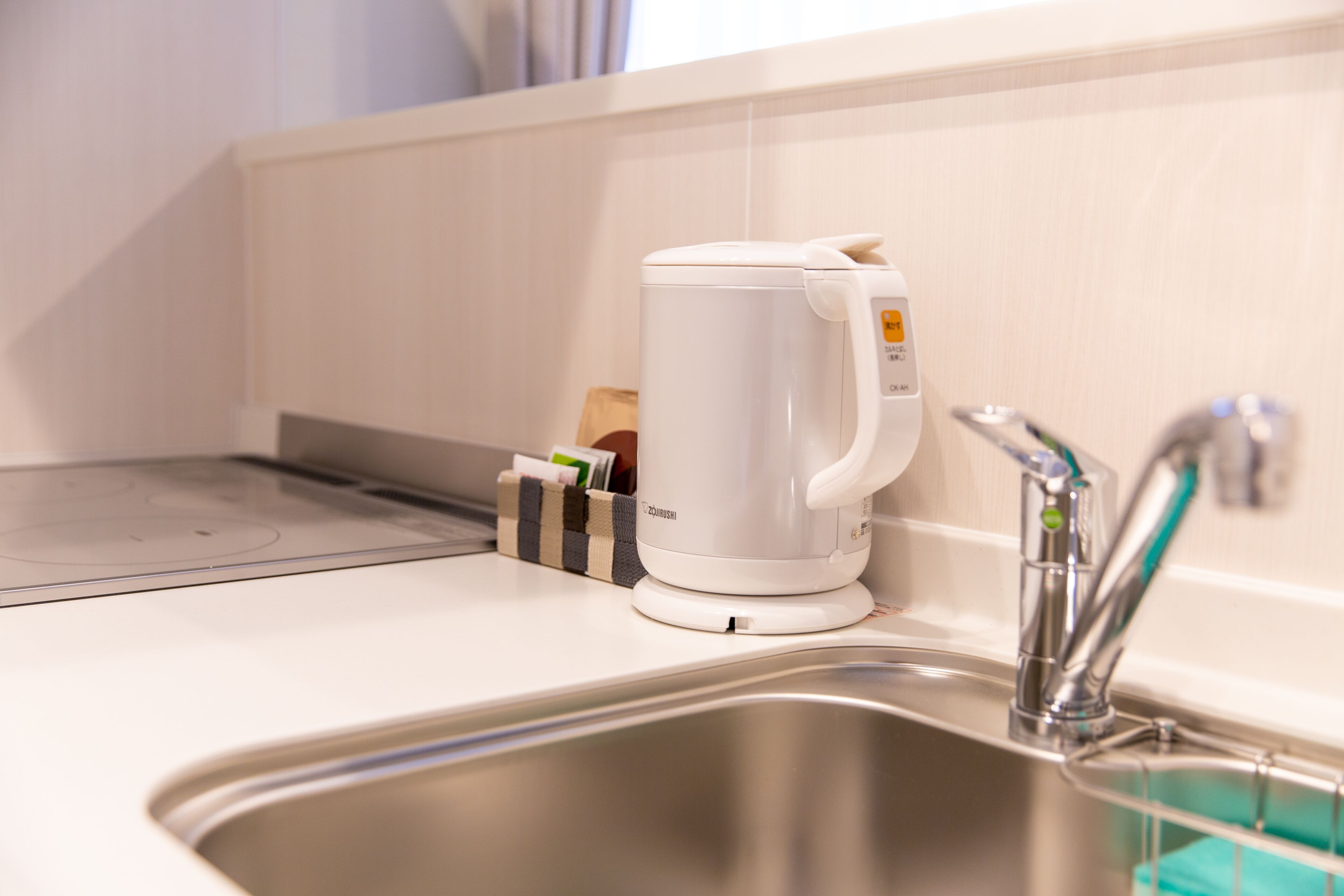 A modern kitchen with a built-in electric kettle, a stainless steel sink, and a soap dispenser.