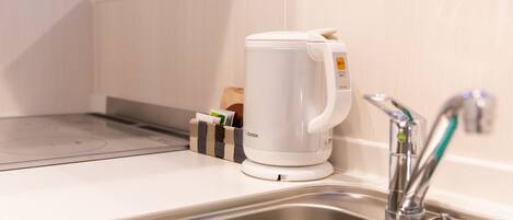 A modern kitchen with a built-in electric kettle, a stainless steel sink, and a soap dispenser.