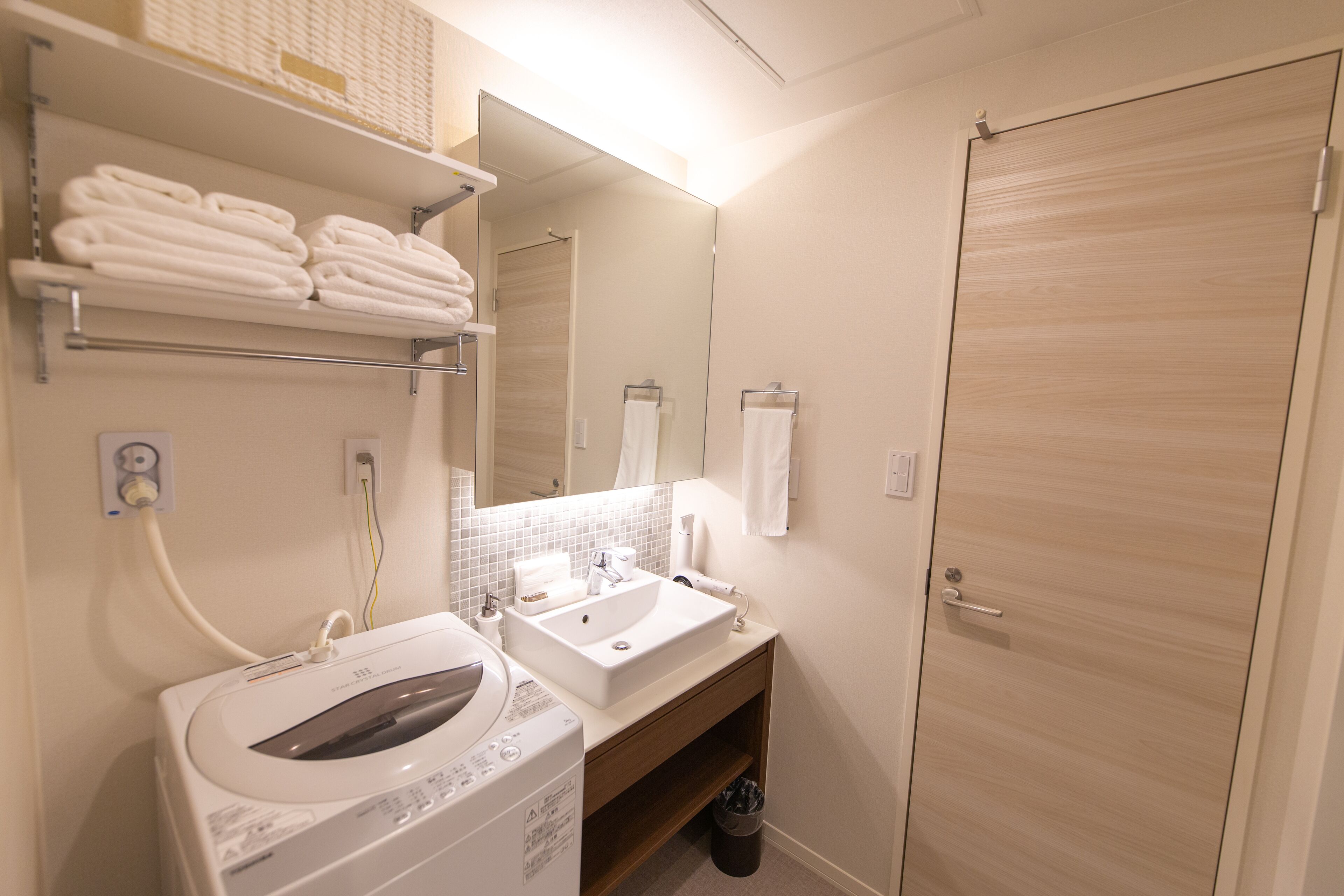 A modern bathroom with a sink, mirror, and stacked towels.