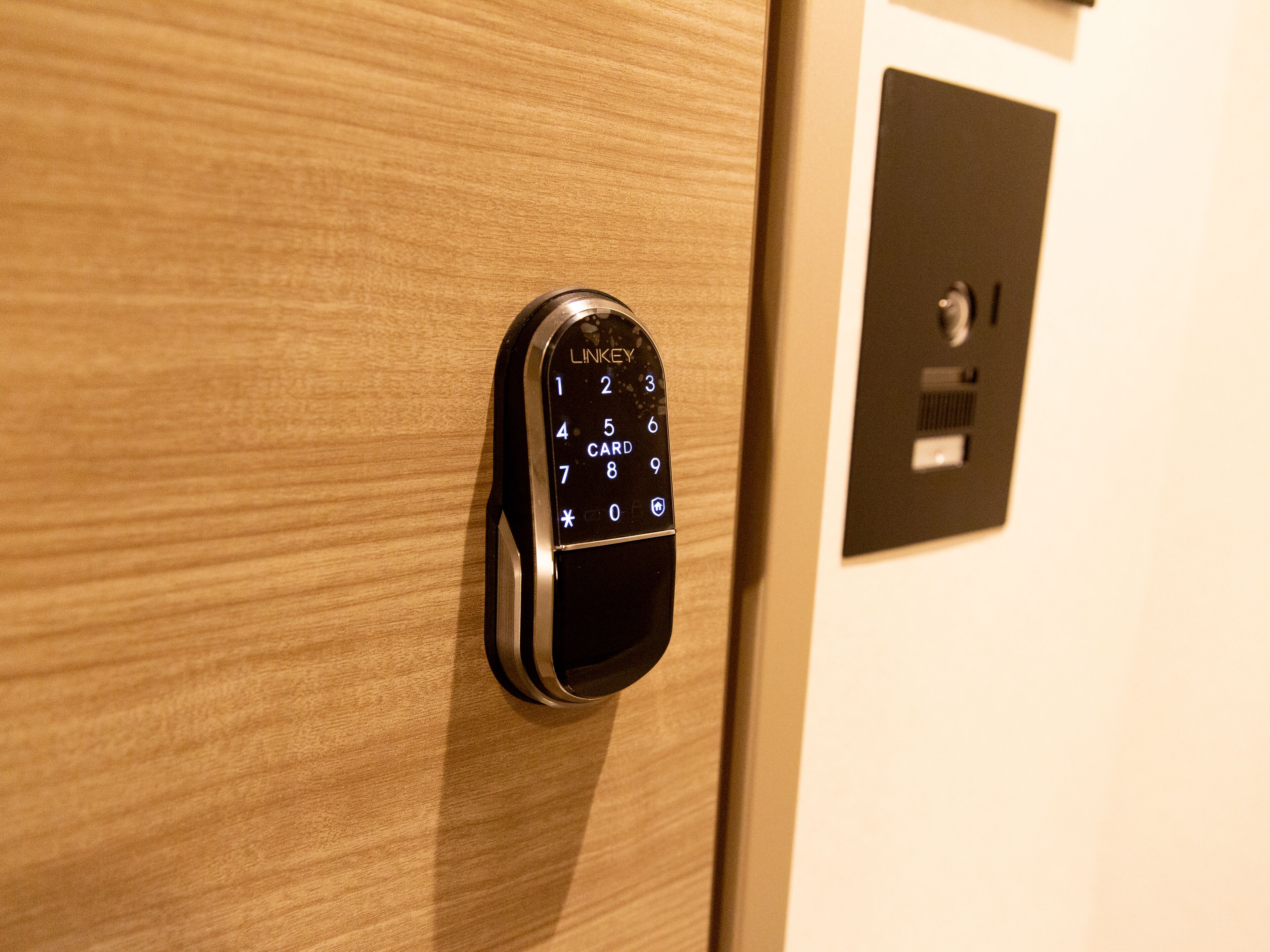 A digital keypad lock on a wooden door, likely for room access.