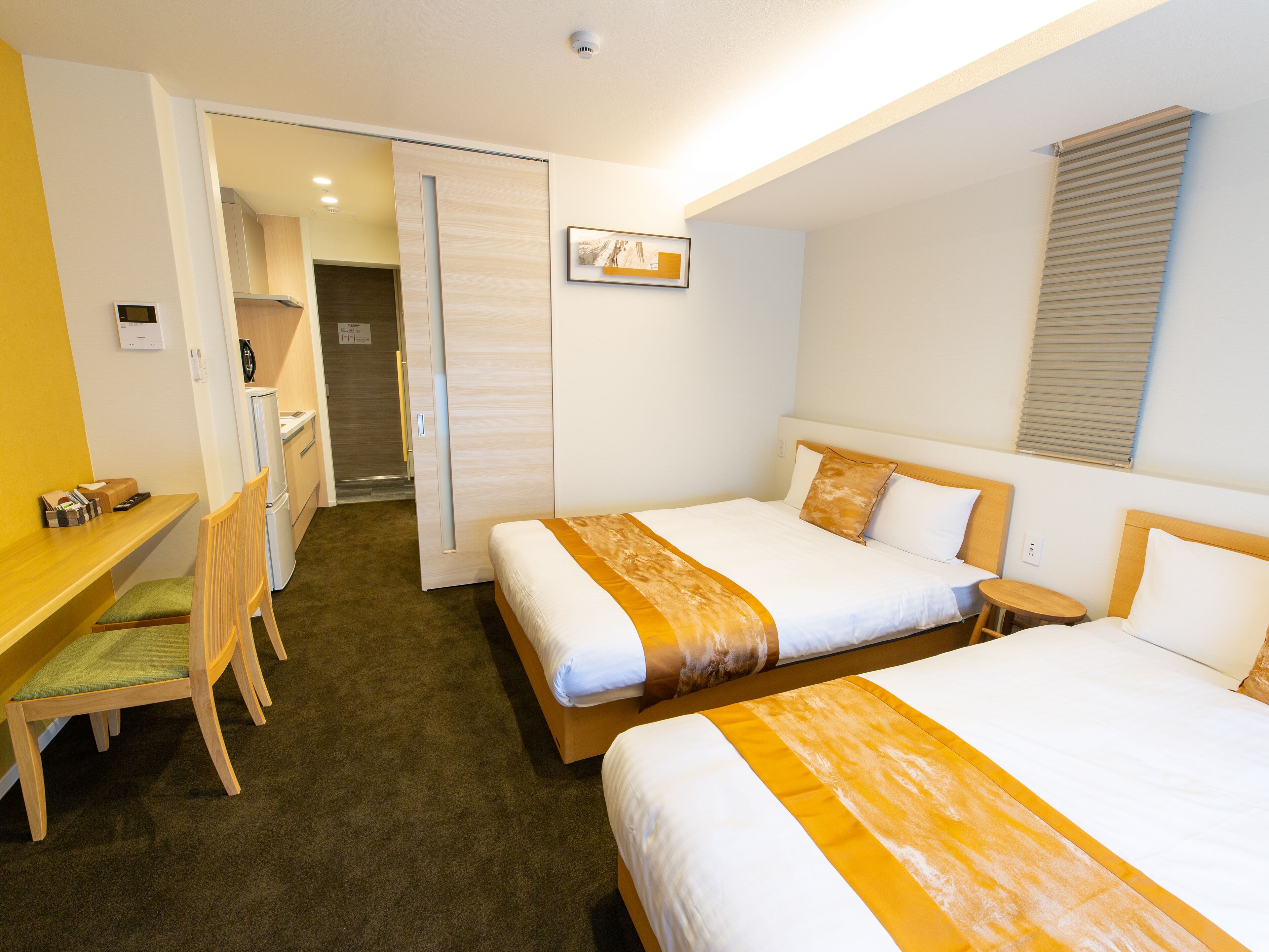 Quarto de hotel com duas camas, uma mesa e uma cadeira.