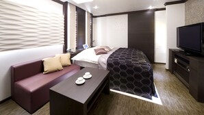 Une chambre d’hôtel moderne équipée d’un lit, d’un canapé, d’une télévision et d’une petite table avec des tasses.
