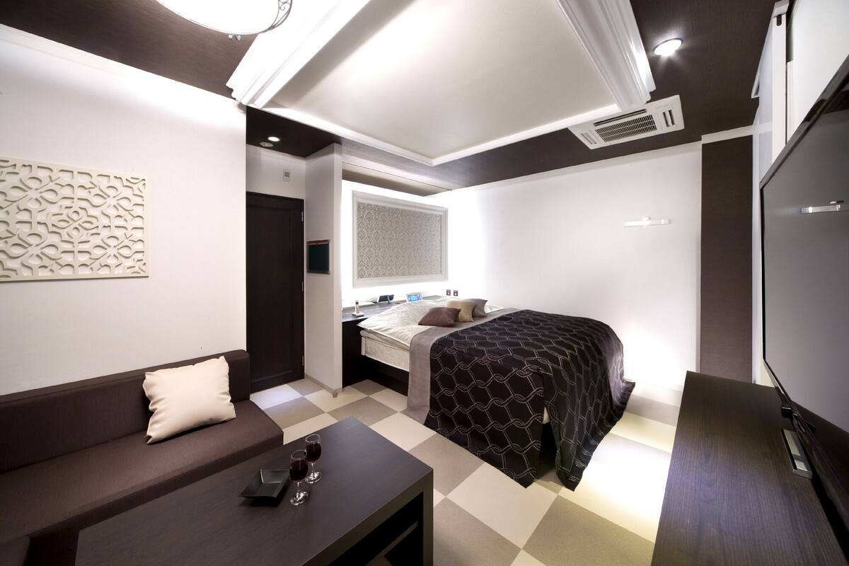 Ein modernes Hotelzimmer mit Bett, Sofa, Schreibtisch und Fernseher.