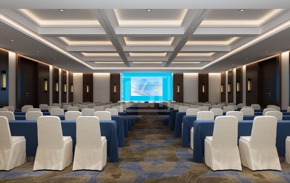A conference room with rows of chairs, a large screen at the front, and a patterned carpet.