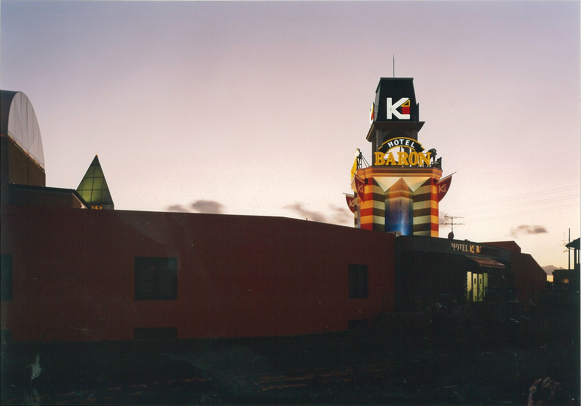 A hotel with a prominent 'K' sign, a red facade, and a small window.