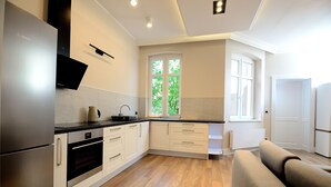 Una cocina moderna con electrodomésticos de acero inoxidable, armarios blancos y suelo de madera.