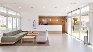 Un área de recepción moderna con un sofá, sillas y un mostrador.