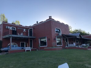 A two-story building with a red exterior, a balcony, and a car parked in front.