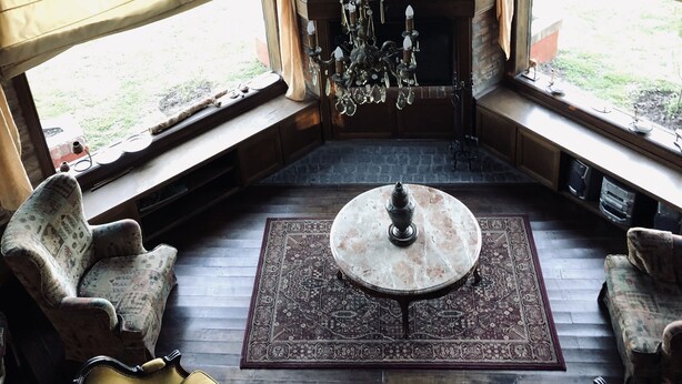 Une pièce dotée d’une grande fenêtre, d’un lustre et d’une table ronde surmontée d’un tapis.
