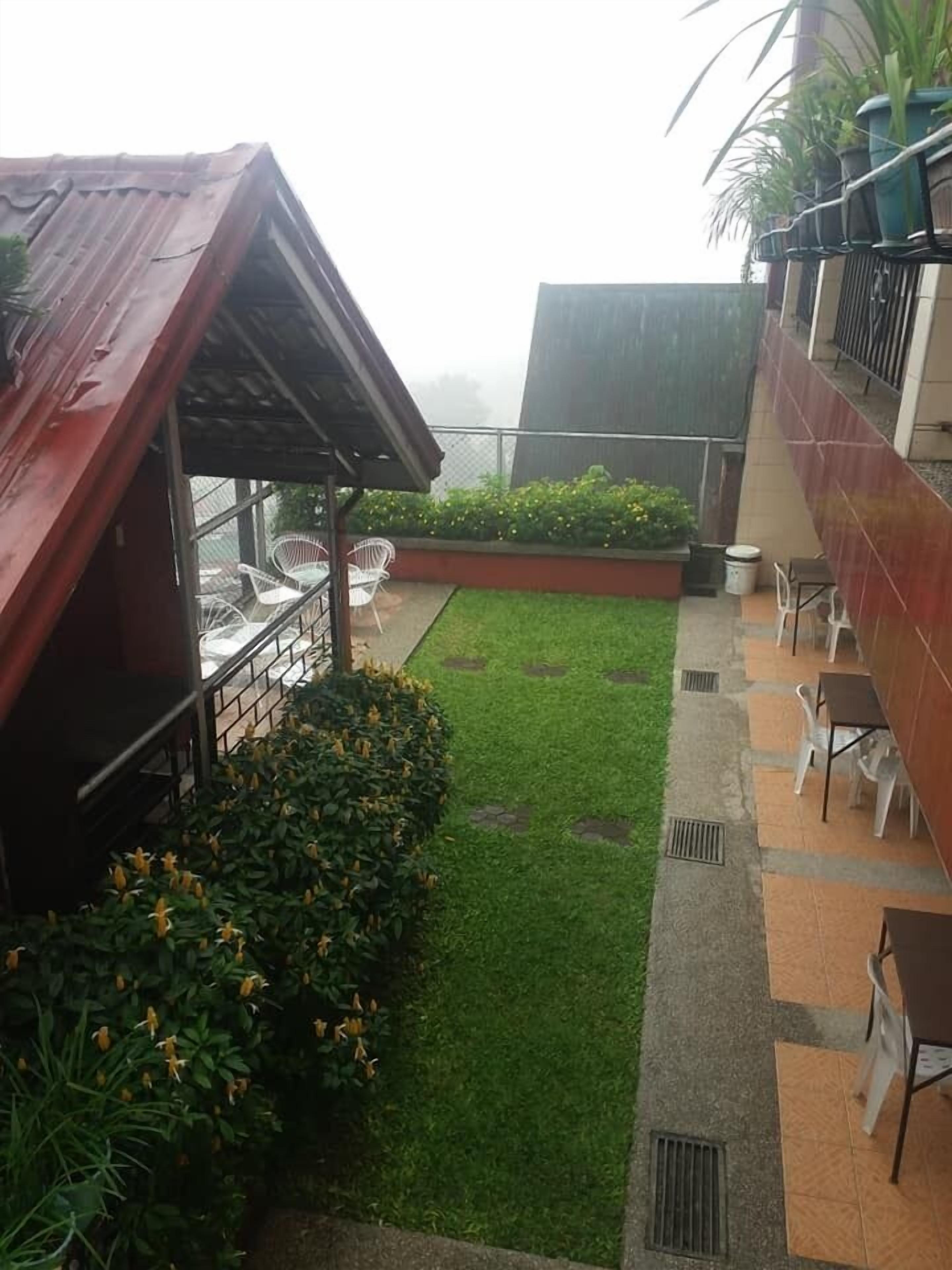 A rooftop terrace with a small lawn, outdoor seating area, and potted plants.