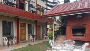 A courtyard with outdoor seating, a barbecue area, and a building with red-tiled roof and balconies. - Nardi-Mar Transient House (Baguio)