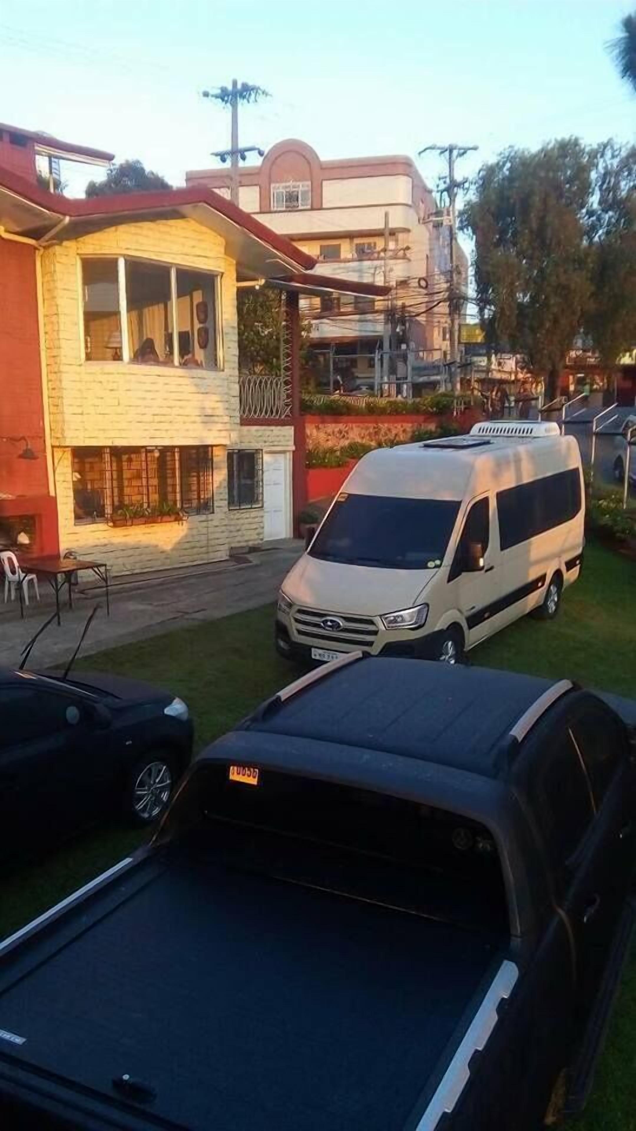A white van parked in front of a building with a balcony.