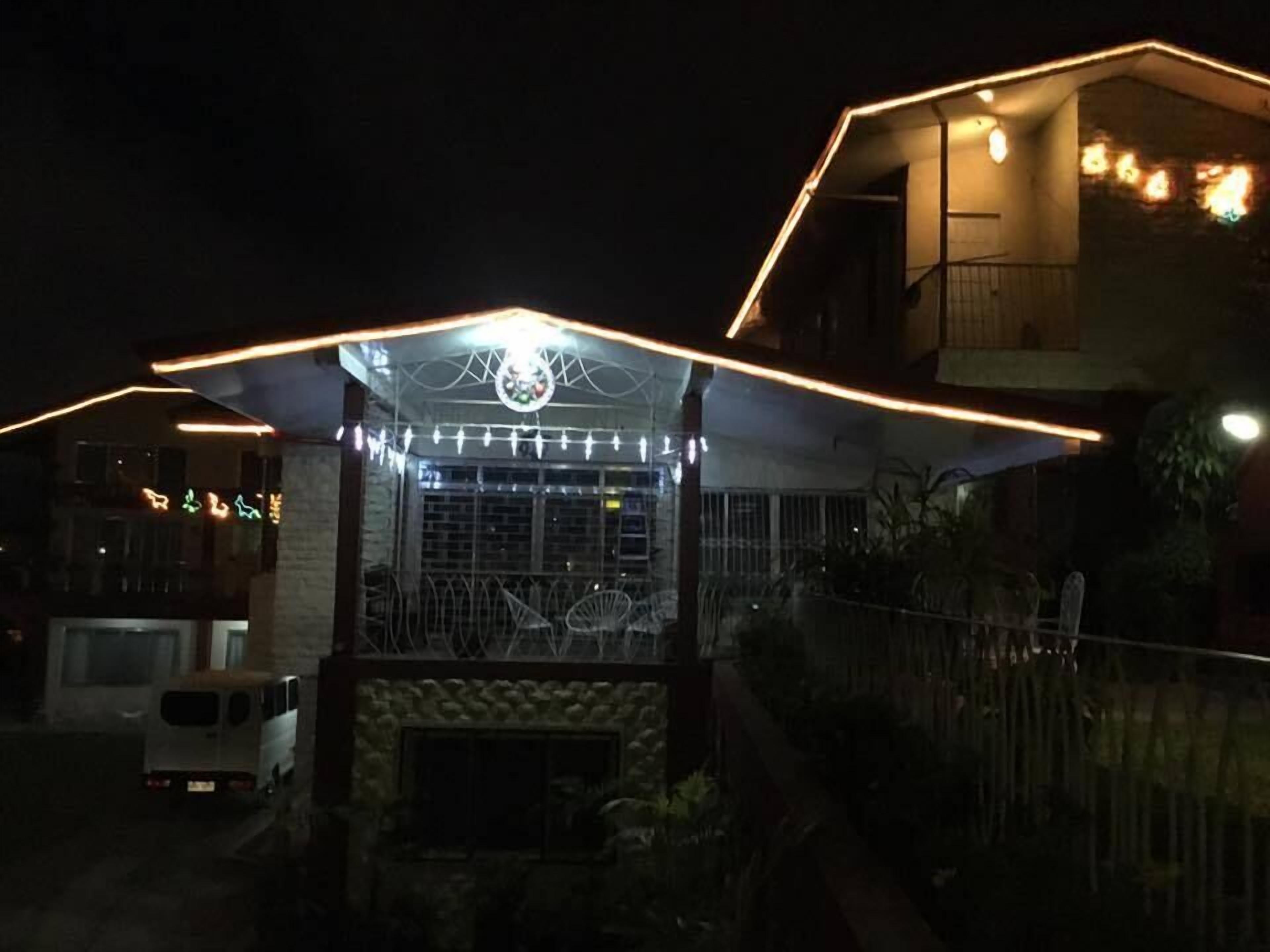 Un edificio con fachada de piedra, una reja metálica y un pequeño porche con luces colgantes.