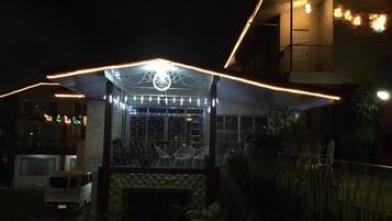 Un edificio con fachada de piedra, una reja metálica y un pequeño porche con luces colgantes.