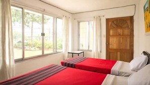 A room with two beds, large windows, a small table, and a wooden door. - Nardi-Mar Transient House (Baguio)