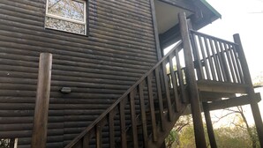Une cabane en bois avec un escalier en bois menant à un balcon.