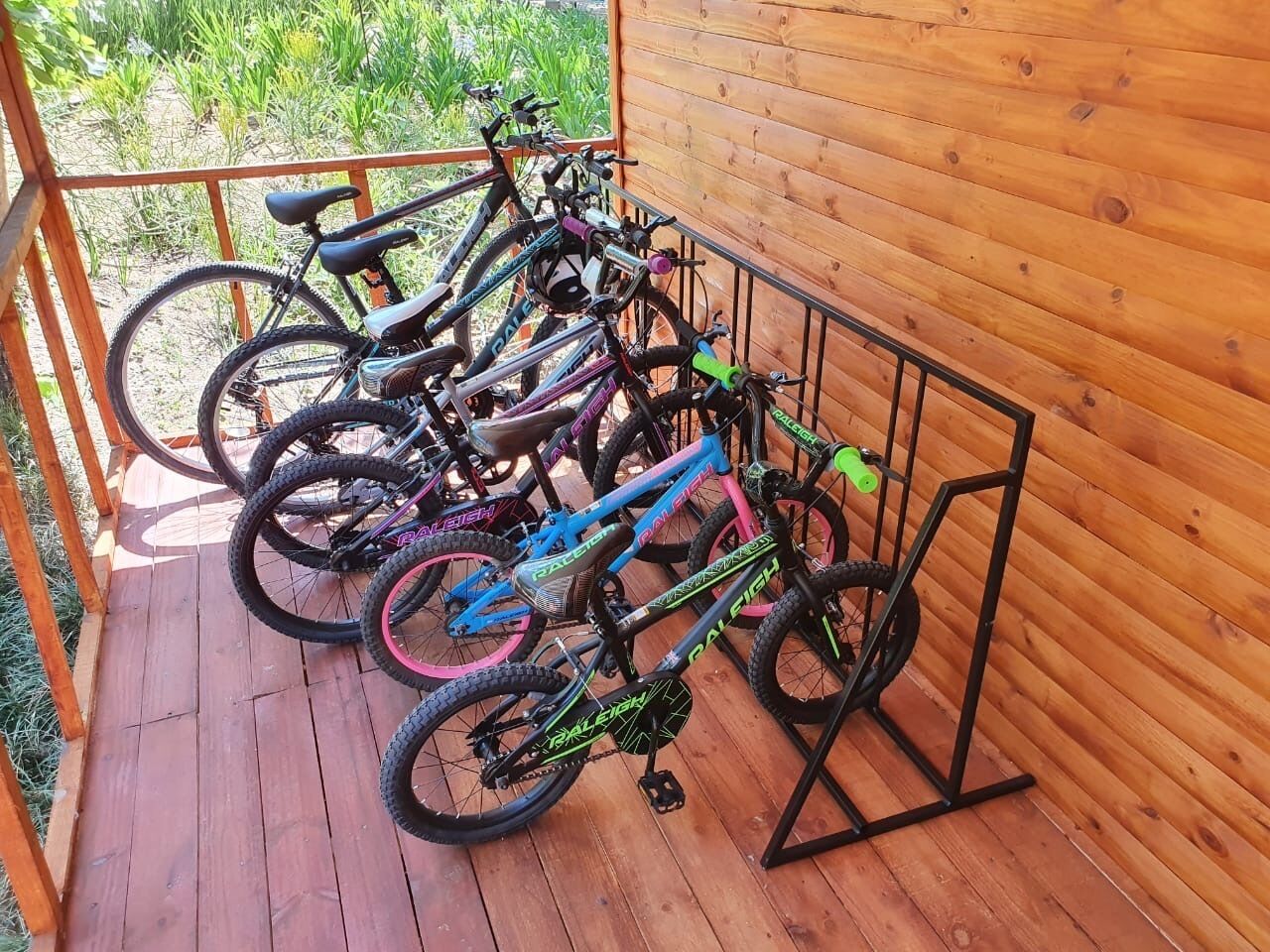 Una terraza de madera con un aparcamiento metálico para bicicletas que contiene varias bicicletas.