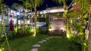 A well-lit outdoor area with a stone pathway leading to a building entrance, surrounded by lush greenery and palm trees. - Melica Resort & Spa Phu Quoc (Phu Quoc)