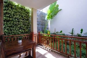 Un balcón de madera con barandilla, una mesa de comedor y una planta en maceta.