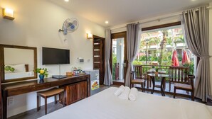 A hotel room with a bed, a desk with a computer, a TV, a minibar, and a balcony with outdoor seating. - Melica Resort & Spa Phu Quoc (Phu Quoc)