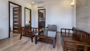 A modern living room with a glass-top coffee table, wooden sofas, and a patterned rug. - Melica Resort & Spa Phu Quoc (Phu Quoc)